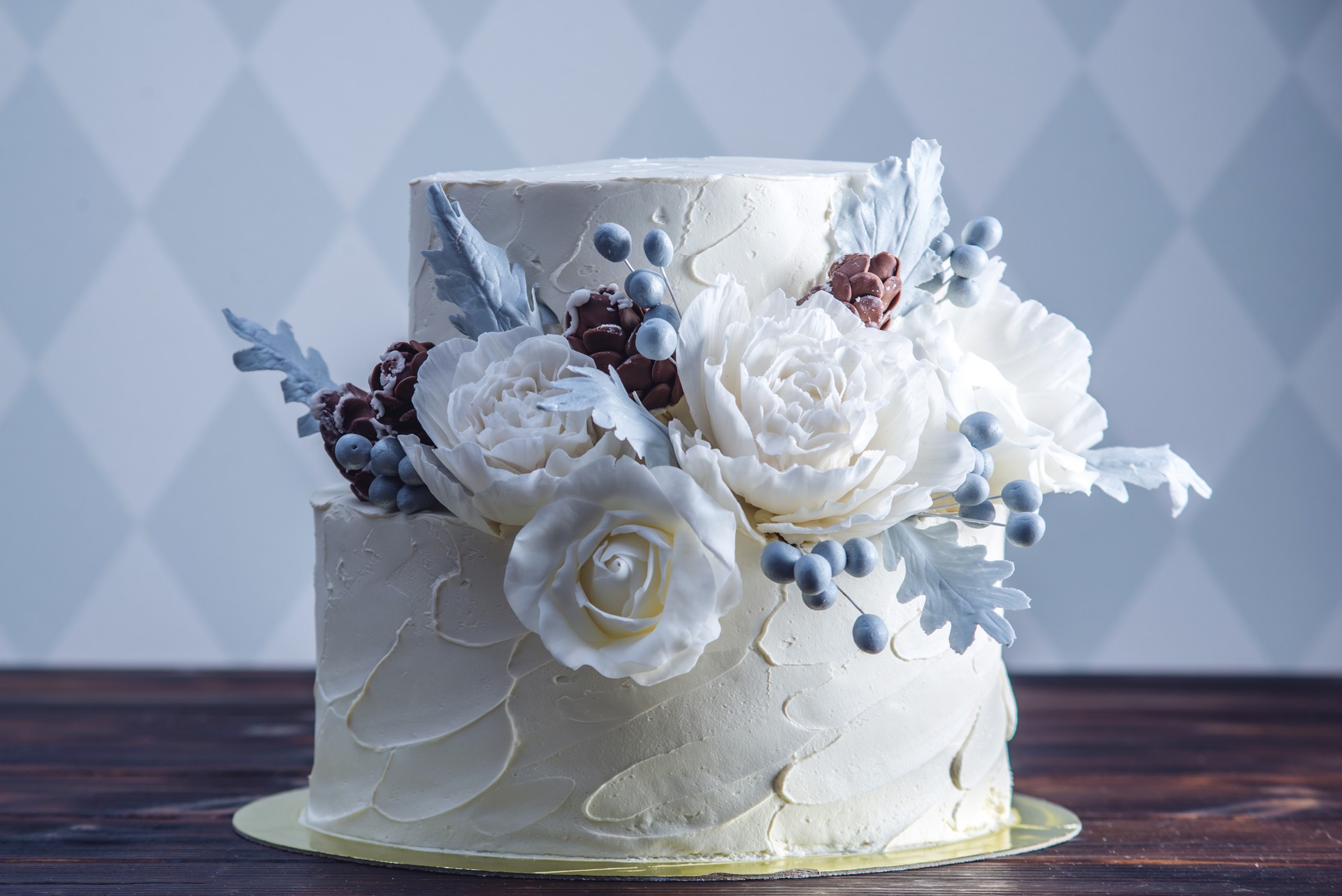 Delicate white bunk wedding cake decorated with an original design using mastic roses. Concept of festive desserts